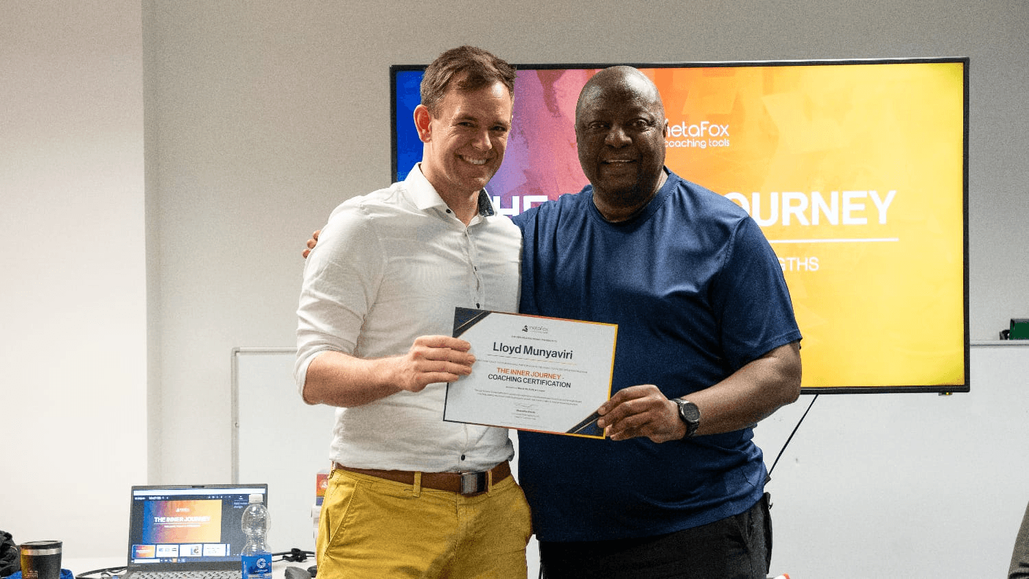 Client handing over a certificate to Lloyd Munyaviri